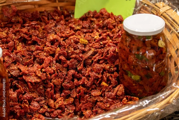 Fototapeta Sun-dried red cherry tomatoes in a wicker basket with price in a street food market in Bari, close up