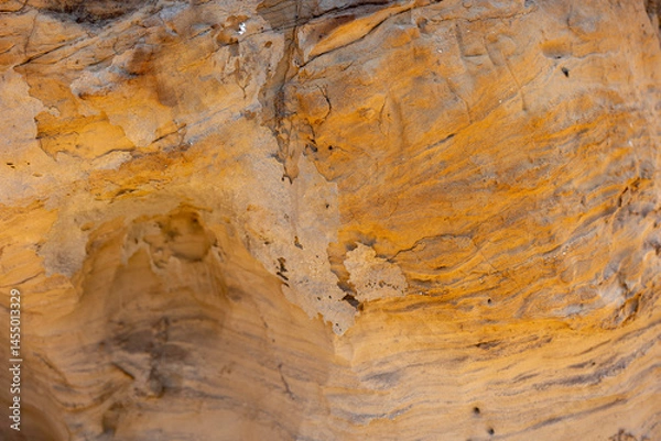 Fototapeta Textured rock surface displays rich colors and patterns in natural setting during daylight hours