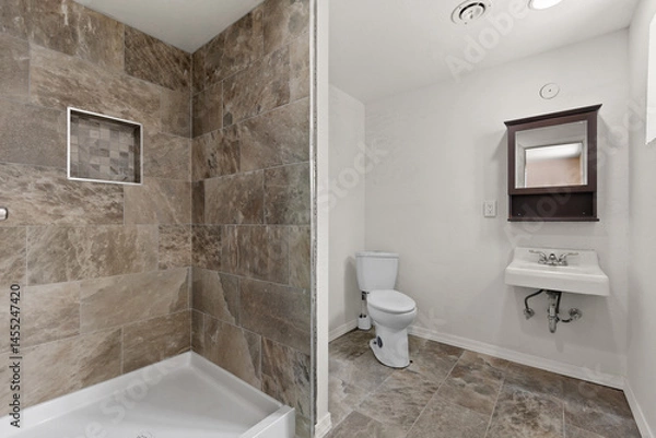 Fototapeta A bathroom that includes a toilet, sink, and a shower area as well