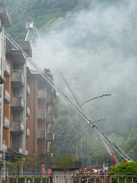 Fototapeta Group of Italian firefighters put out a fire on the roof of an apartment building using ladder trucks
