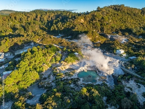 Fototapeta Aerial view of the Wai-O-Tapu geothermal area in New Zealand. Steam rises from the hot springs, surrounded by lush vegetation and a boardwalk for visitors. A popular tourist destination.
