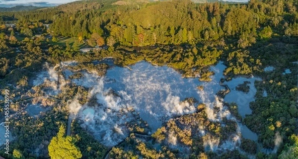 Fototapeta Aerial view of Wai-O-Tapu geothermal area, near Rotorua, New Zealand. Steam rises from the hot springs, surrounded by lush forest. Tourists visit to experience the unique landscape.