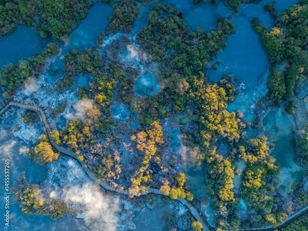 Fototapeta Aerial view of Wai-O-Tapu geothermal area in New Zealand. A wooden boardwalk allows tourists to safely view the hot springs and bubbling mud pools. Steam rises from the geothermal activity.