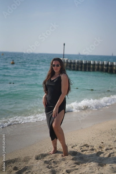 Fototapeta Woman in Black Dress Posing on Beach