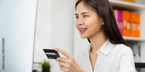Fototapeta female hand holding credit card and type on laptop keyboard with online payment for shopping.