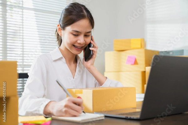 Fototapeta Young Asian businesswoman working talking to customers from order online and packing on the box.
