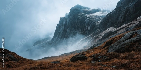 Obraz Misty Cliffside Mountain Rising Above Golden Grass Hillside in Autumn Light, Dramatic Landscape with Steep Rocky Slopes, Rugged Nature Scene Evoking Solitude, Wilderness, and Majestic Elevation