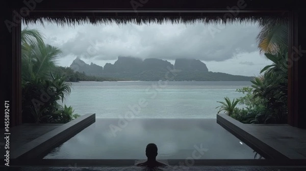 Obraz A tranquil scene of a person relaxing in a plunge pool, overlooking a dramatic tropical vista of mountains and water, with overcast skies