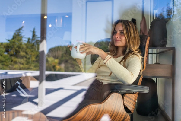 Obraz Woman by the window at home, with tea or coffee mug on her hand. Good morning, feeling good