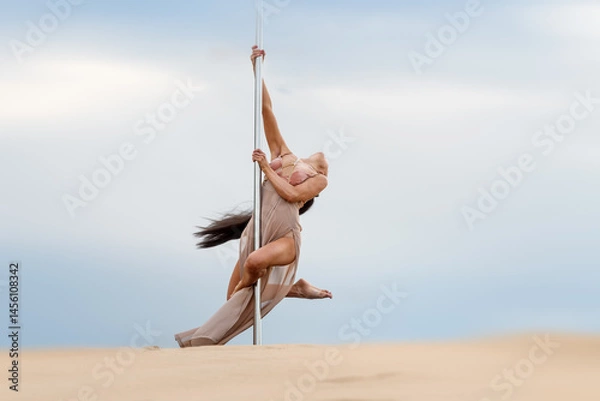 Fototapeta A girl in a light dress spins on a pole.