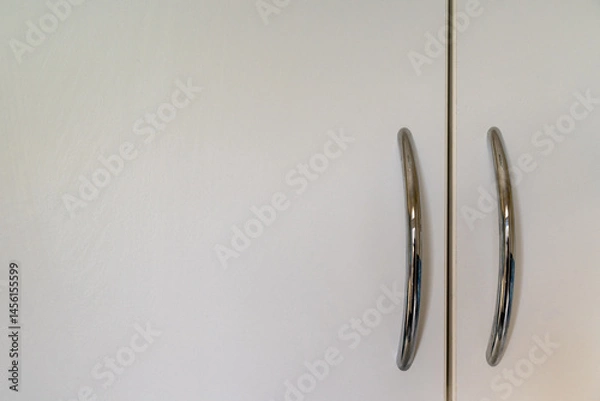 Fototapeta White cupboard doors with silver-colored handles positioned to the right. Copy space to left.