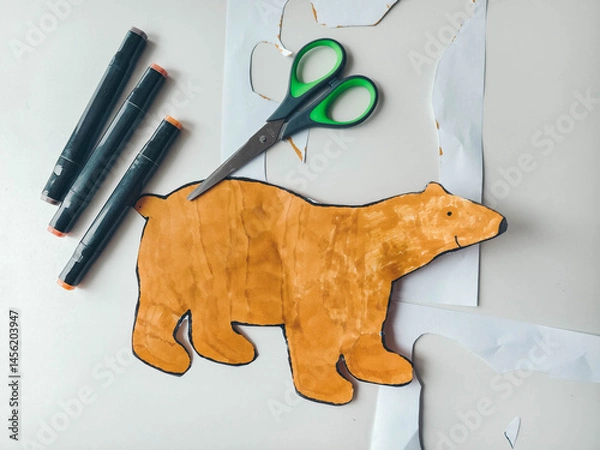Obraz Bear figure cut out with scissors on white table. Children's creativity.