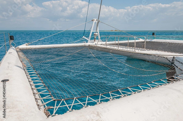 Fototapeta Catamaran netting is taut, providing a clear view of the mesmerizing blue water below