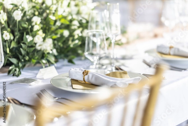 Fototapeta A wedding table covered with a white tablecloth, decorated with flowers, candles, glasses and cutlery