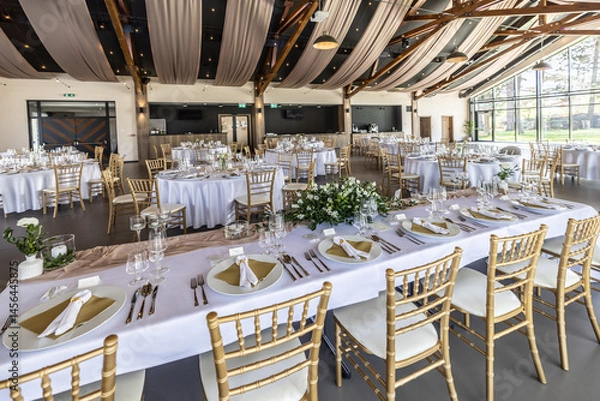 Fototapeta Wedding setting and decorated tables in a beautiful modern interior of a performance hall with a modern light ceiling of wooden construction