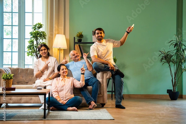 Obraz Sitting on sofa and sweating, Indian family cools down after daughter turns on AC with remote