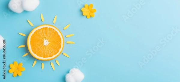 Fototapeta Orange slice as sun with white cotton clouds on blue background. Vitamin C and cosmetic concept. Image for skincare, health products, social media banner and advertisement with copy space.