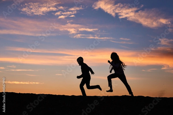 Fototapeta children running on the background of sunset sky