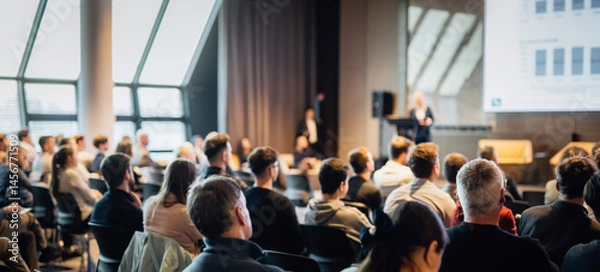 Fototapeta Speaker giving a talk in conference hall at business event. Rear view of unrecognizable people in audience at the conference hall. Business and entrepreneurship concept