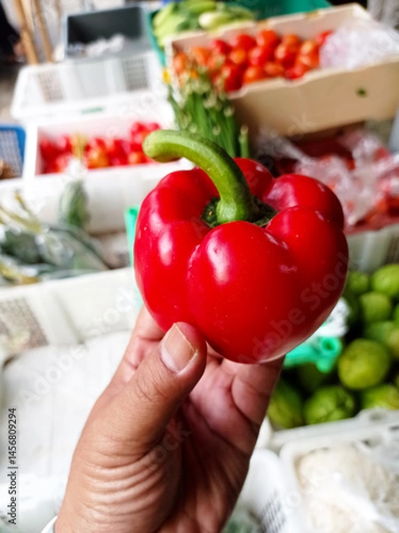 Fototapeta Close-up of red bell pepper held by hand
