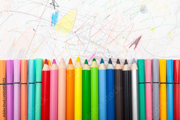Obraz Multi-colored pencils lie on white paper drawn with multi-colored curved lines.