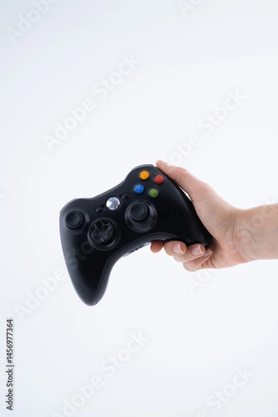Fototapeta Black Gaming Controller Held in Hand on White Background