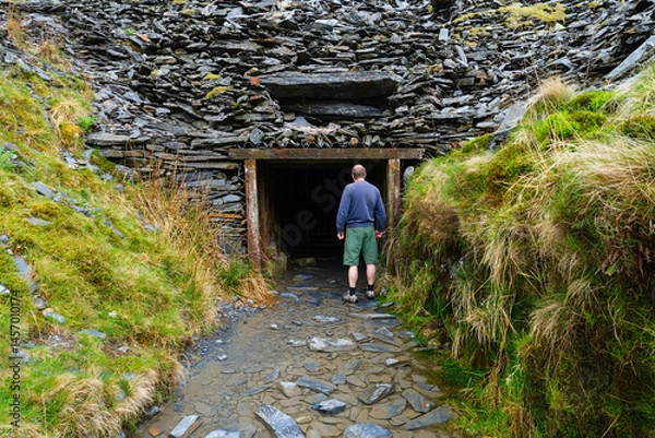 Fototapeta A man is walking next to a slate mine tunnel entrance