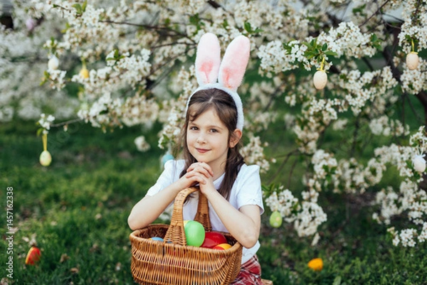Fototapeta Easter egg hunt. Girl child Wearing Bunny Ears Running To Pick Up Egg In Garden. Easter tradition. Baby with basket full of colorful eggs.