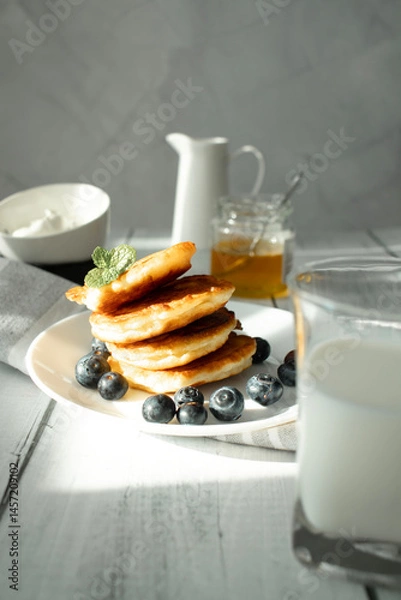 Fototapeta Cottage cheese pancakes with blueberries and sour cream on a white wooden table