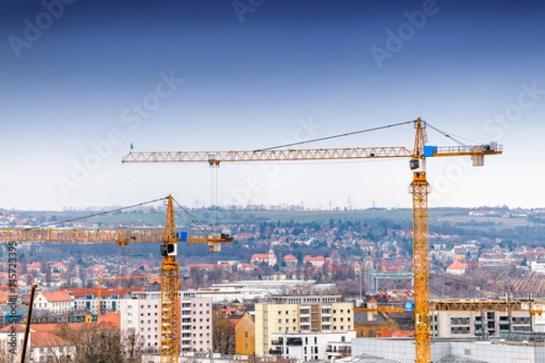 Fototapeta Industrial background with construction cranes over blue sky