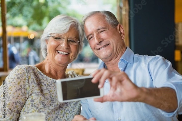 Fototapeta Happy senior couple taking selfie on mobile phone
