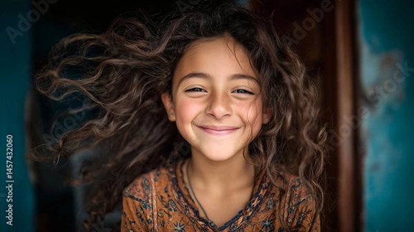 Fototapeta Niña sonriente con cabello rizado al viento en exterior
