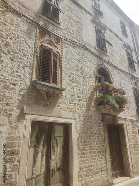 Fototapeta Old Stone Building with Shuttered Windows and Flower Boxes in Historic Town