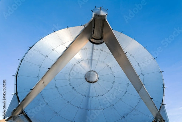 Obraz The shiny metallic surface of a radio telescope dish set against a clear blue sky