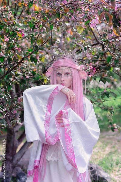 Fototapeta Deer dryad girl against the background of a blooming pink apple tree