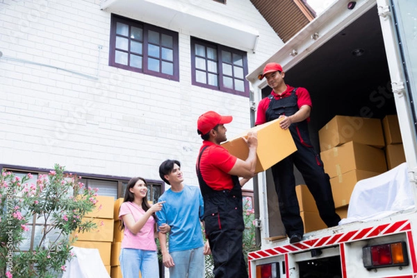 Fototapeta Asian couple newlywed looking to professional delivery logistic moving house worker lifting or uploading house furniture, multiethnic Indian and Caucasian teamwork employees business service concept