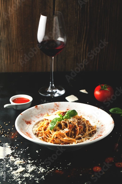 Fototapeta Pyszny makaron bolognese z mięsem, parmezanem, bazylią i lampką wina