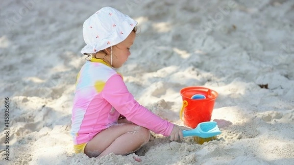 Fototapeta Little girl playing with sand on beach