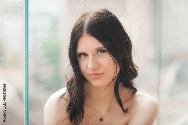 Obraz A stylish young girl captures a confident selfie in a vibrant urban environment. With flowing hair and a chic outfit, she embodies the essence of modern fashion and social media influence