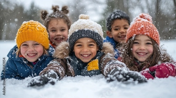 Fototapeta Group of children smiling and playing together in the snow during a winter day outside having fun