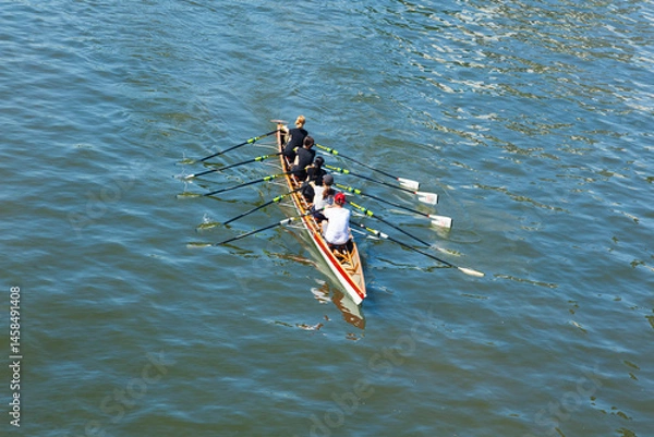 Obraz Academic rowing, four athletes with a coxswain sail in a boat on open water. Academic rowing competition.