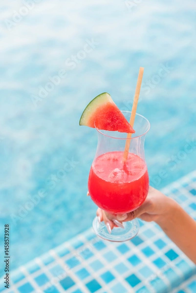 Fototapeta Refreshing Watermelon Juice by the Poolside in Summer. Close-up of a Woman’s Hand Holding a Watermelon Punch