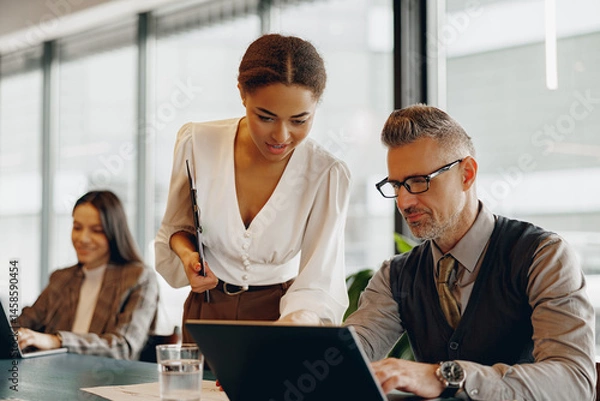 Obraz A dedicated business team working together on a project within a modern office environment to achieve success