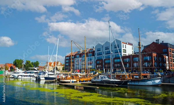 Fototapeta Scenic view of a marina on a sunny day, featuring a variety of yachts docked along the pier in Gdansk, Poland. Picturesque waterfront scene.