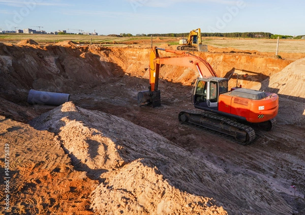 Obraz Excavator during laying sewer pipes, water lines, sanitary sewers, storm sewers. Excavator on groundwork. Sewage drainage at construction site. Building construction. Excavator on earthworks