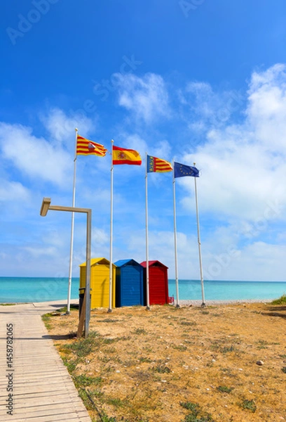 Obraz Beach changing rooms with Spain flag. Colourful changing cabins on sea beach. Colorful changing cabins. Coast Bathing Box at seaside. Bathing boxes for changing. Multicolored change rooms on beach.
