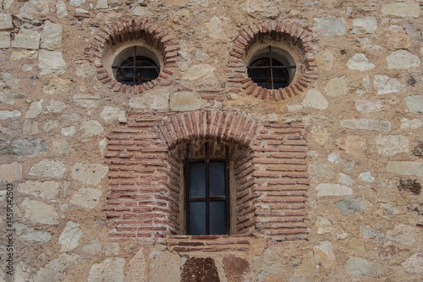 Fototapeta Pareidolia. Two circular windows and an elongated window, which looks like a face in a stone wall in the town of Pedraza, province of Segovia. Spain