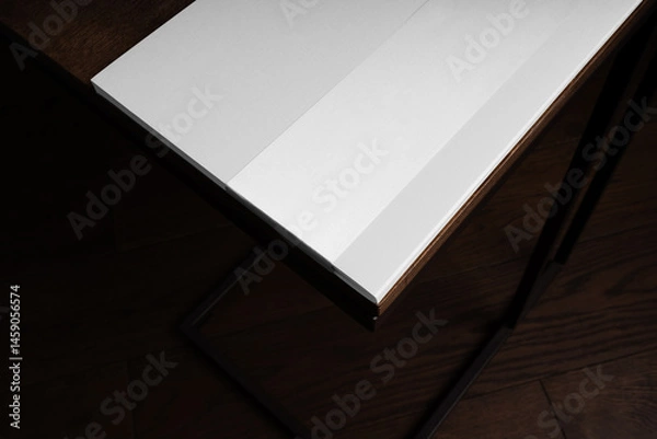 Fototapeta A brochure closeup mockup placed on a wooden table in a dark cozy room with wooden floor. Isolated blank surface to place your design.