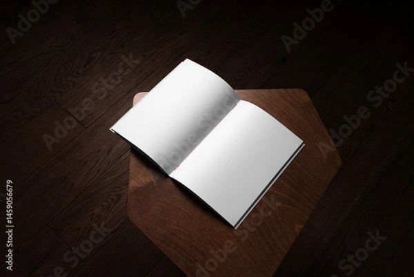 Fototapeta An open book mockup placed on a wooden table in a dark cozy room with wooden floor. Isolated blank surface to place your design.