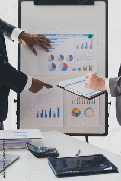 Obraz Businessman making a presentation at work in front of colleague. Businessman coach mentor explain graph chart on flipchart corporate group workshop training in meeting room.